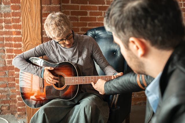 guitar teacher guides student lesson